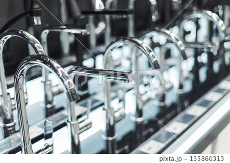 Rows of sleek chrome faucets displayed in a showroom, representing modern bathroom and kitchen design 135860313