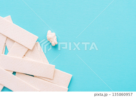 Chewing gum sticks scattered on turquoise background, copy space Chewing gum sticks scattered on turquoise background, copy space 135860957