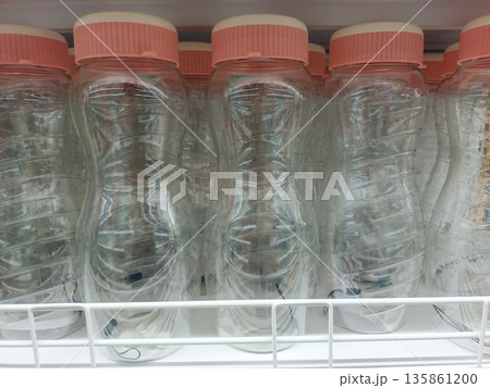 Clear Plastic Water Bottles with Pink Caps in a Row on Store Shelf for Daily Hydration 135861200