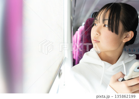 電車の窓から外を見る10代の女性 135862199