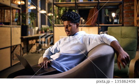 Young man working on laptop in modern coworking environment. Young man working on laptop in modern coworking environment. 135862456