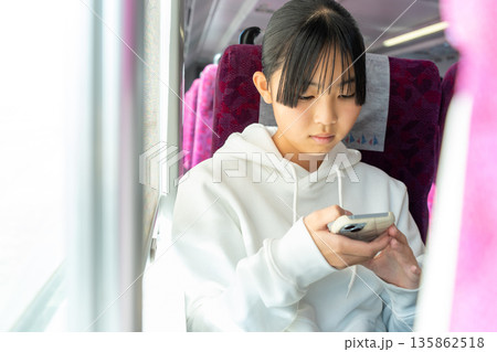 電車内でスマホを使う女子学生 135862518