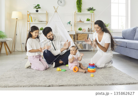 Happy parents and children playing with toys, clapping hands and having fun together Happy parents and children playing with toys, clapping hands and having fun together 135862627