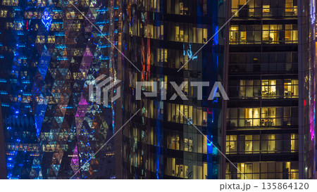 Windows timelapse of the multi-storey building of glass and steel office lighting and working people within 135864120