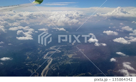 飛行機の窓から見下ろす雲海と山脈を流れる大河 135864342