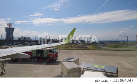 搭乗前の空港通路から見える飛行機の翼と青い空 135864347