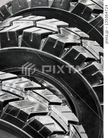 Close view of three rugged tires stacked in a workshop setting during daylight hours 135864724