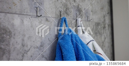Terry bathrobes hang on hooks in the bathroom 135865684