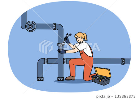 Woman plumber repairs pipes in factory, using wrench to fix crack in industrial pipeline 135865875