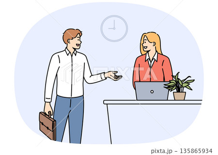 Man rents hotel room while talking to administrator standing near reception desk with laptop 135865934
