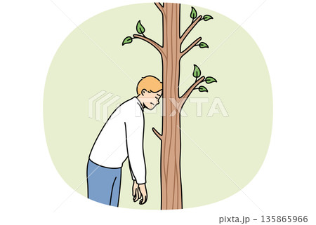 Tired man rests forehead on tree to rest after long walk in fresh air, stands alone in forest 135865966