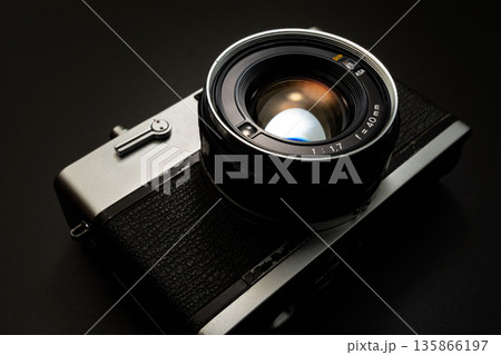 暗い背景にスポットライトが当たった古いフィルムカメラ 暗い背景にスポットライトが当たった古いフィルムカメラ 135866197