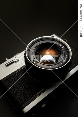 暗い背景にスポットライトが当たった古いフィルムカメラ 暗い背景にスポットライトが当たった古いフィルムカメラ 135866198