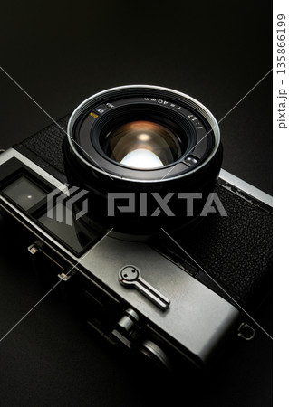 暗い背景にスポットライトが当たった古いフィルムカメラ 135866199