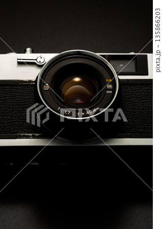 暗い背景にスポットライトが当たった古いフィルムカメラ 暗い背景にスポットライトが当たった古いフィルムカメラ 135866203