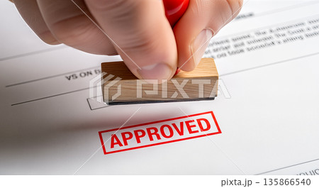Hand holding wooden rubber stamp pressing approved word in red ink on paper document business contract agreement permission success finance deal 135866540