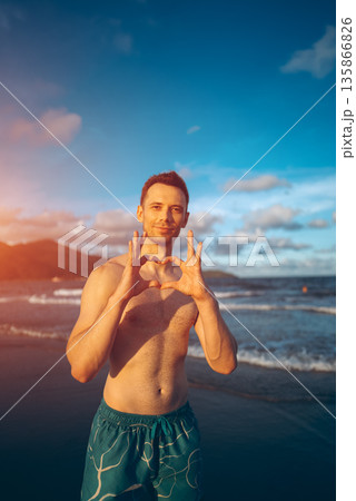 handsome white man with athletic muscular body standing at beach at sunny sunset, attractive male athlete walking at sea or ocean shore handsome white man with athletic muscular body standing at beach at sunny sunset, attractive male athlete walking at sea or ocean shore 135866826