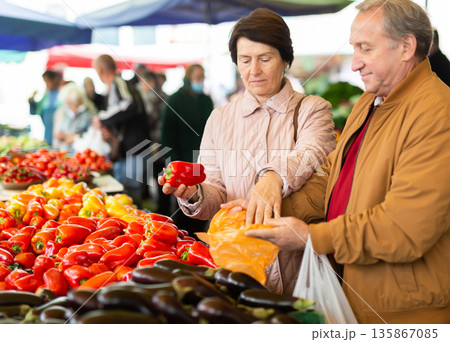 elderly man and woman buy pepper at an open market 135867085