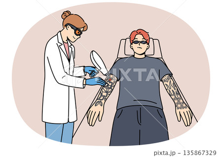 Procedure for laser tattoo removal from guy arms, with professional woman doctor. 135867329