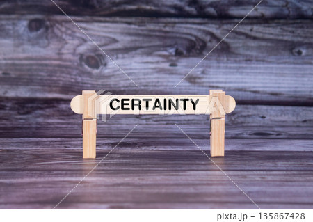 Certainty symbol. A wooden stick secured by Clothespins set over beautiful Realistic Wooden Texture Background. Business and Certainty concept with copy space 135867428
