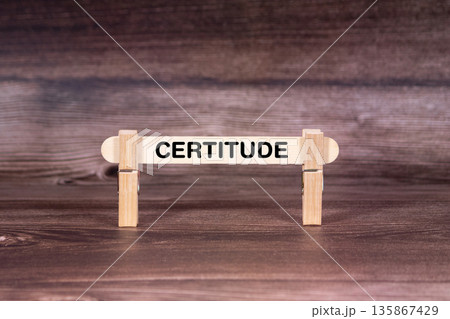 Certitude symbol. Clothespins gripping a wooden stick against a beautiful Brown Wooden Background . Business and Certitude concept with copy space 135867429