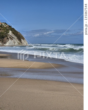 a serene view of the sea from the shore, with gentle waves and a clear blue sky 135867544