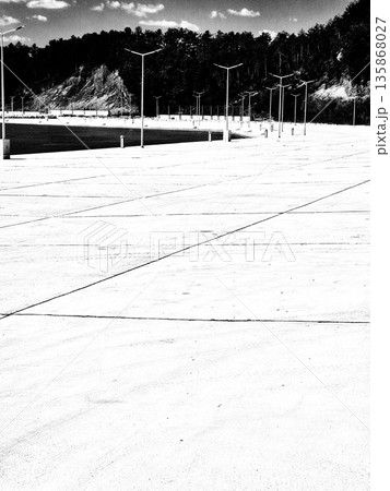 Modern waterfront. Calm body of water with concrete pier and modern street lights. black and white photo 135868027