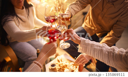 Friends clinking wine glasses during home wine tasting evening. Friends clinking wine glasses during home wine tasting evening. 135869511