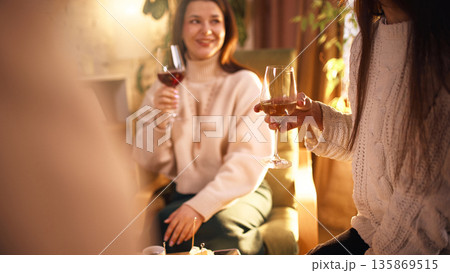 Friends enjoying wine tasting together in cozy living room. Friends enjoying wine tasting together in cozy living room. 135869515