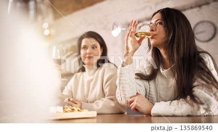 Woman enjoying white wine during relaxed lifestyle evening indoors. 135869540