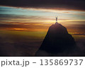 Successful male celebrates victory on a mountain top, raising hands up like a winner. Conceptual and motivational scene inspiring for overcoming challenges. Courageous and victorious person 135869737