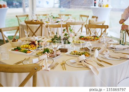 Elegant wedding menu displayed on a beautifully set table with gourmet dishes, fine glassware, and floral decorations, creating a romantic dining atmosphere for guests Elegant wedding menu displayed on a beautifully set table with gourmet dishes, fine glassware, and floral decorations, creating a romantic dining atmosphere for guests 135869797