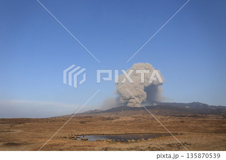 野焼き後の阿蘇中岳 火山活動で立ち上る噴煙と黒く焼けた草千里 135870539