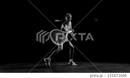 Black and white female tennis player hitting backhand shot. 135871006