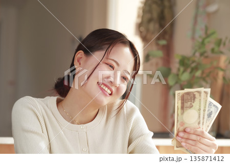 お金を手にして嬉しそうな女性 135871412
