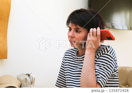A woman listens to a sent voice message on her phone A woman listens to a sent voice message on her phone 135871426