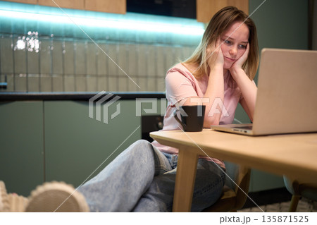 Evening home office scene with woman staring at laptop Evening home office scene with woman staring at laptop 135871525