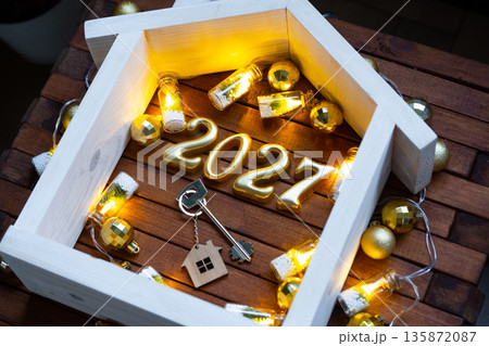 Golden figures number 2027 and tiny home on background of cozy windows of a house with warm light with festive decor of stars,snow and garlands. Greeting card, Happy New Year, cozy home Golden figures number 2027 and tiny home on background of cozy windows of a house with warm light with festive decor of stars,snow and garlands. Greeting card, Happy New Year, cozy home 135872087