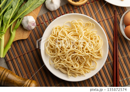 Raw yakisoba noodles in white plate,made from wheat flour and egg.Top view. Raw yakisoba noodles in white plate,made from wheat flour and egg.Top view. 135872574