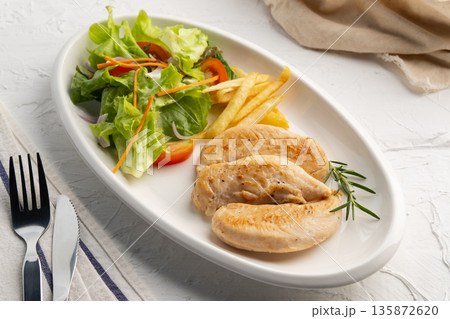 Grilled Black Pepper Chicken fillet with green oak lettuce ,tomatoes,carrot,french fries and onion in white plate. 135872620