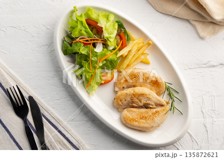 Grilled Black Pepper Chicken fillet with green oak lettuce ,tomatoes,carrot,french fries and onion in white plate. 135872621