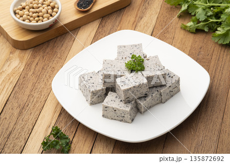 Sliced piece of Tofu mix black sesame seeds in white plate on wooden table 135872692