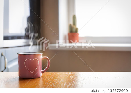 Hot coffee mug on wooden table with cozy kitchen background Hot coffee mug on wooden table with cozy kitchen background 135872960