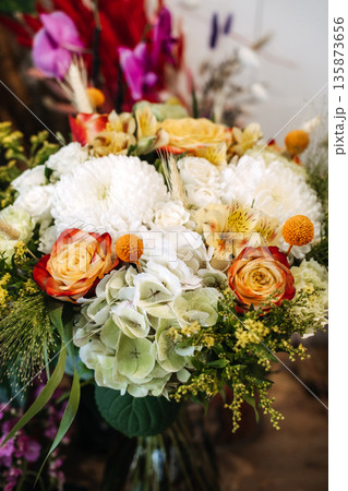 Vibrant mix of roses, hydrangeas, and chrysanthemums forms lush bouquet. Garden-style bouquet, wedding floral trends, natural aesthetics. 135873656