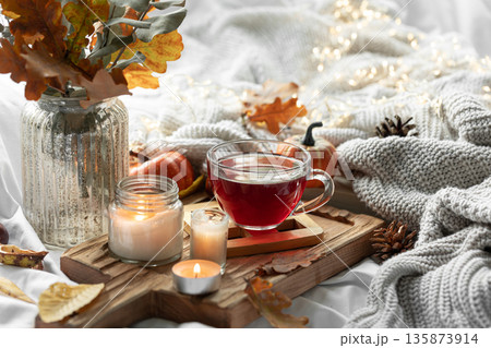 Autumn composition with a cup of tea, leaves and a knitted element. Autumn composition with a cup of tea, leaves and a knitted element. 135873914