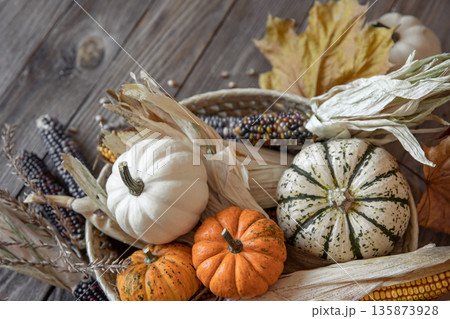 Close-up of pumpkin, corn and autumn leaves on a wooden background. Close-up of pumpkin, corn and autumn leaves on a wooden background. 135873928