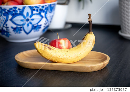 Banana and apple on the kitchen table. Banana and apple on the kitchen table. 135873987