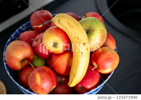 Banana and apples in the kitchen on the kitchen table near the sink. 135873990