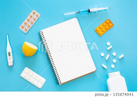 Blank notebook, medicines, pills and thermometer on a blue background, flat lay. 135874041