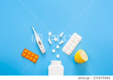 Blue background with pills, thermometer and lemon, flat lay. 135874068